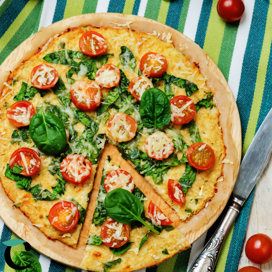 Nahaufnahme von Caulito vegetarischem Low-Carb Blumenkohl-Pizzaboden mit Tomate, Käse und Spinat auf einem Pizzabrett.