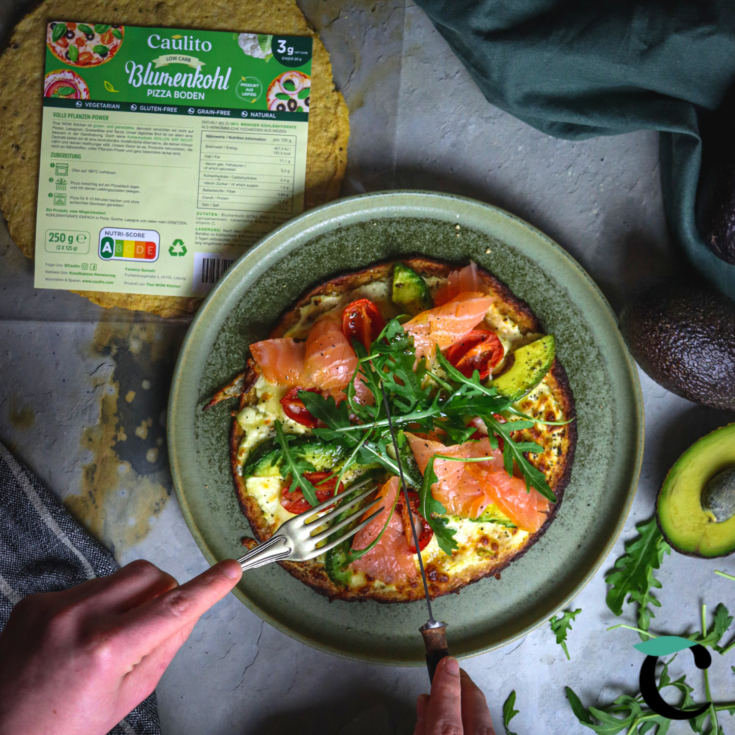 Ein Rezept für Caulito Vegetarische Blumenkohlpizza mit geräuchertem Lachs, Avocado und Rucola. Blumenkohlpizza auf einem rustikalen Hintergrund. Päckchen mit vegetarischer Pizza, verpackt in einer industriellen, kompostierbaren Verpackung.