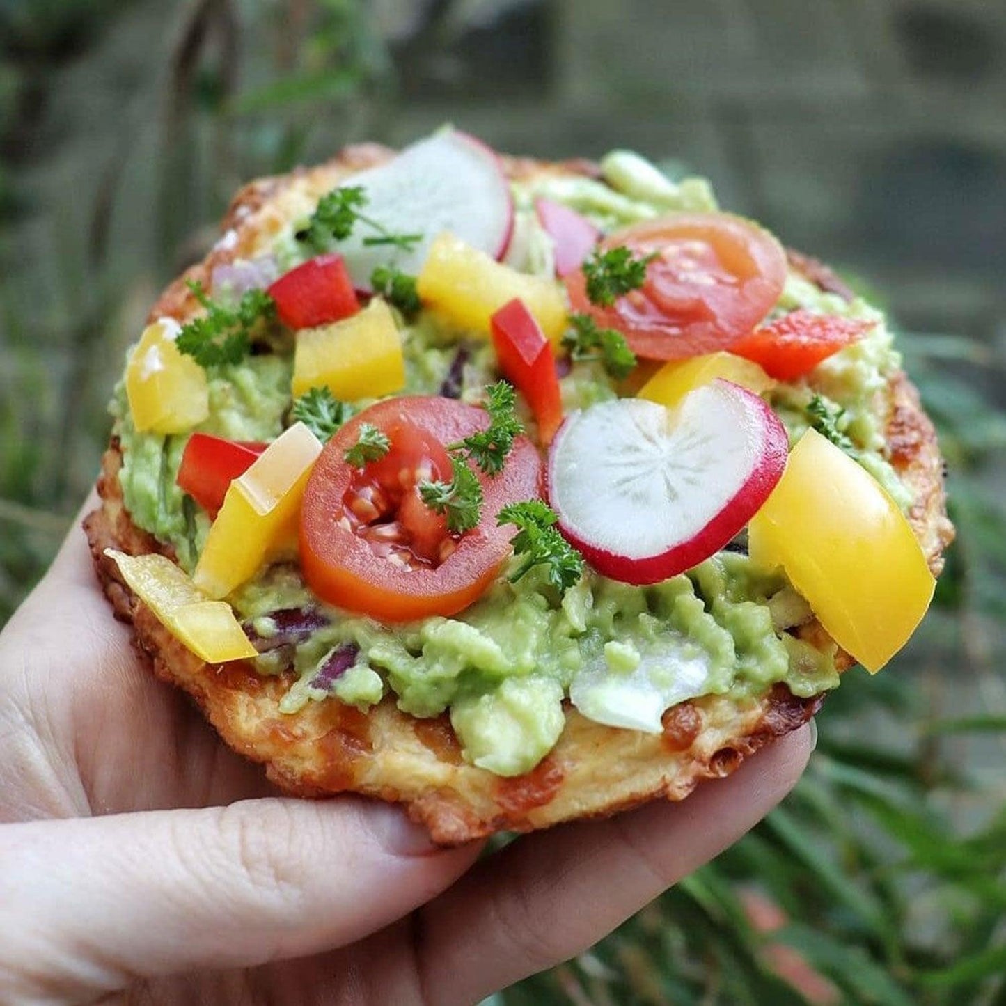 Glutenfreier Blumenkohltoast mit pürierter Avocado, Rote Bete, Tomaten und Paprika im Freien serviert.