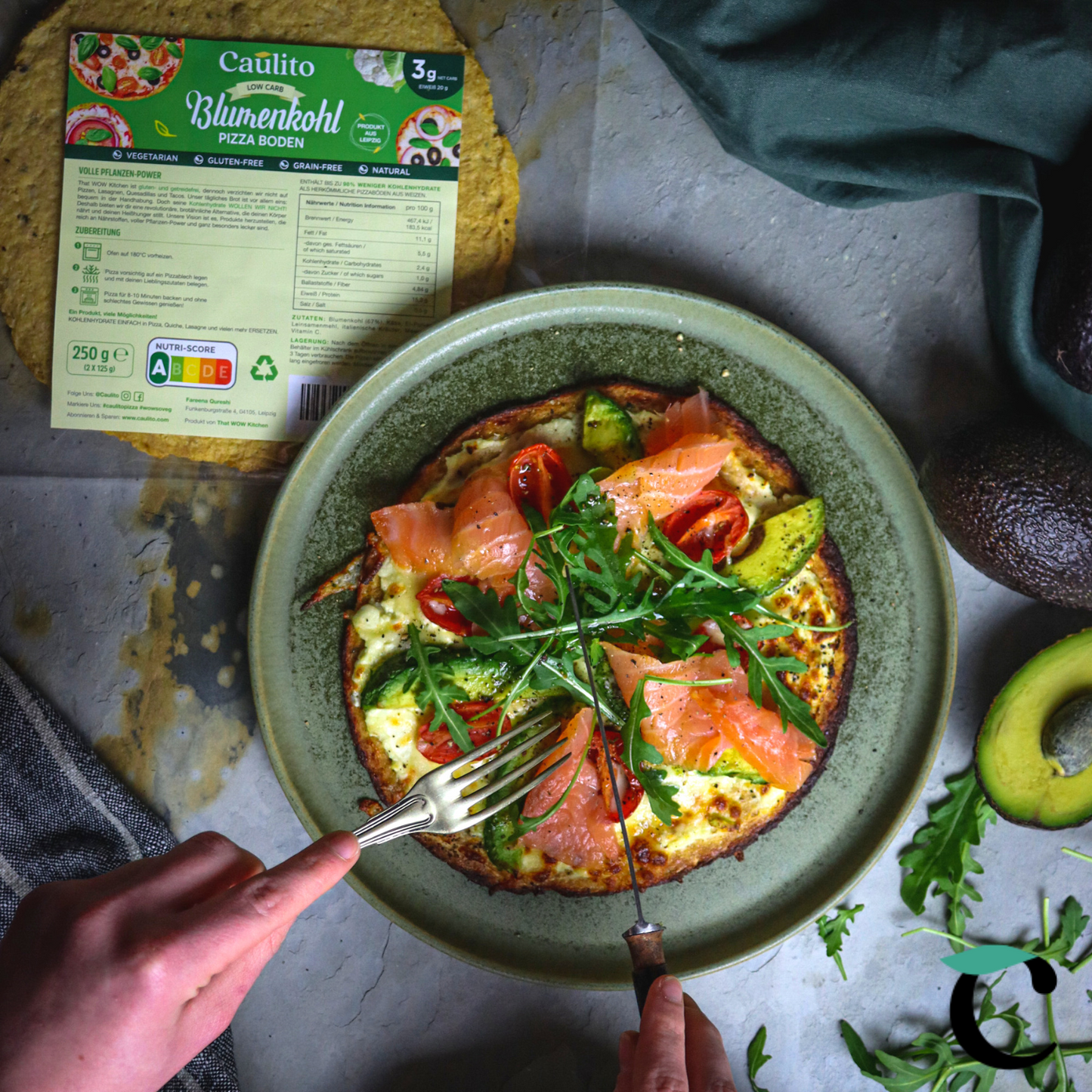 Ein Rezept für Caulito Vegetarische Blumenkohlpizza mit geräuchertem Lachs, Avocado und Rucola. Blumenkohlpizza auf einem rustikalen Hintergrund. Päckchen mit vegetarischer Pizza, verpackt in einer industriellen, kompostierbaren Verpackung. 