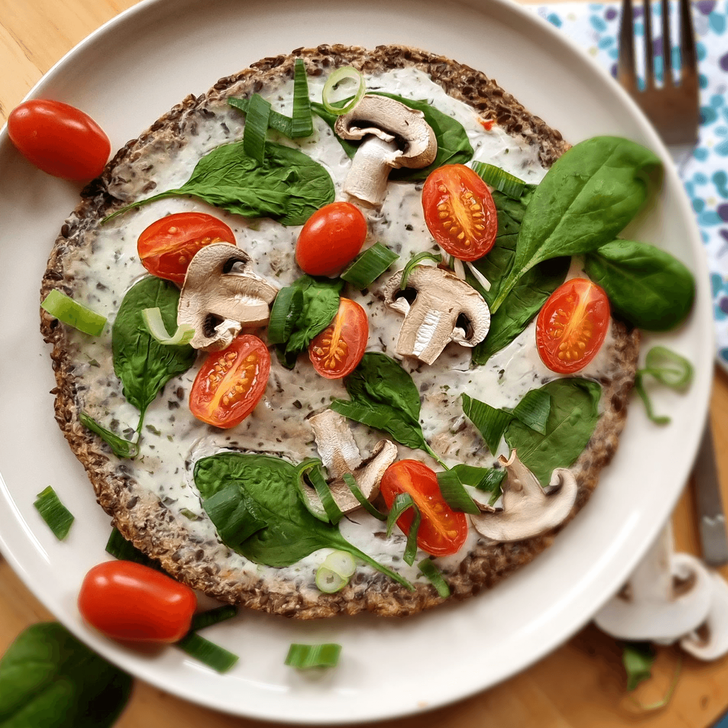 Caulito Vegane Blumenkohl-Pizza Rezeptfoto mit Cashew-Käse, Kirschtomaten, Spinat, Pilzen und Frühlingszwiebeln.